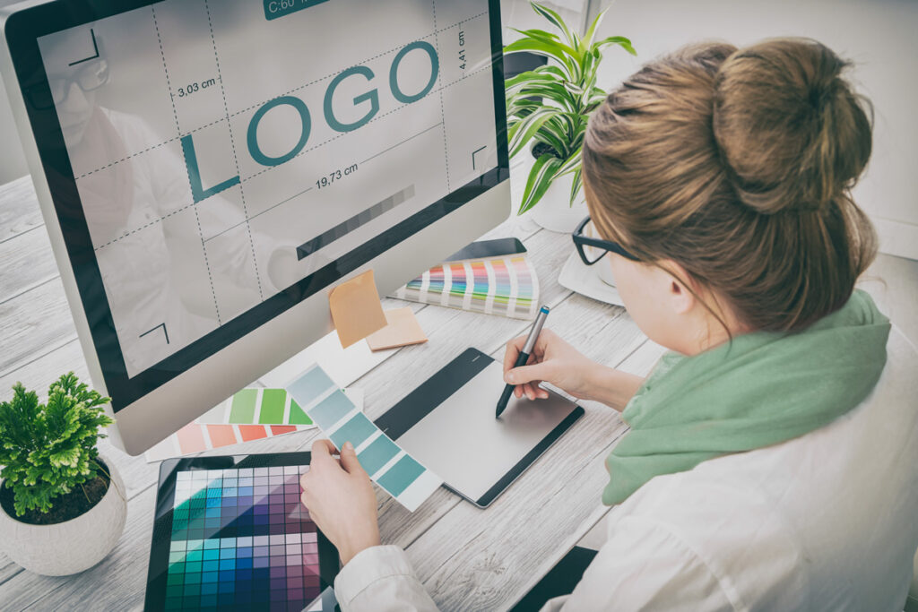 A woman designing her El Paso business’ logo in front of a computer with the word “LOGO” on it.